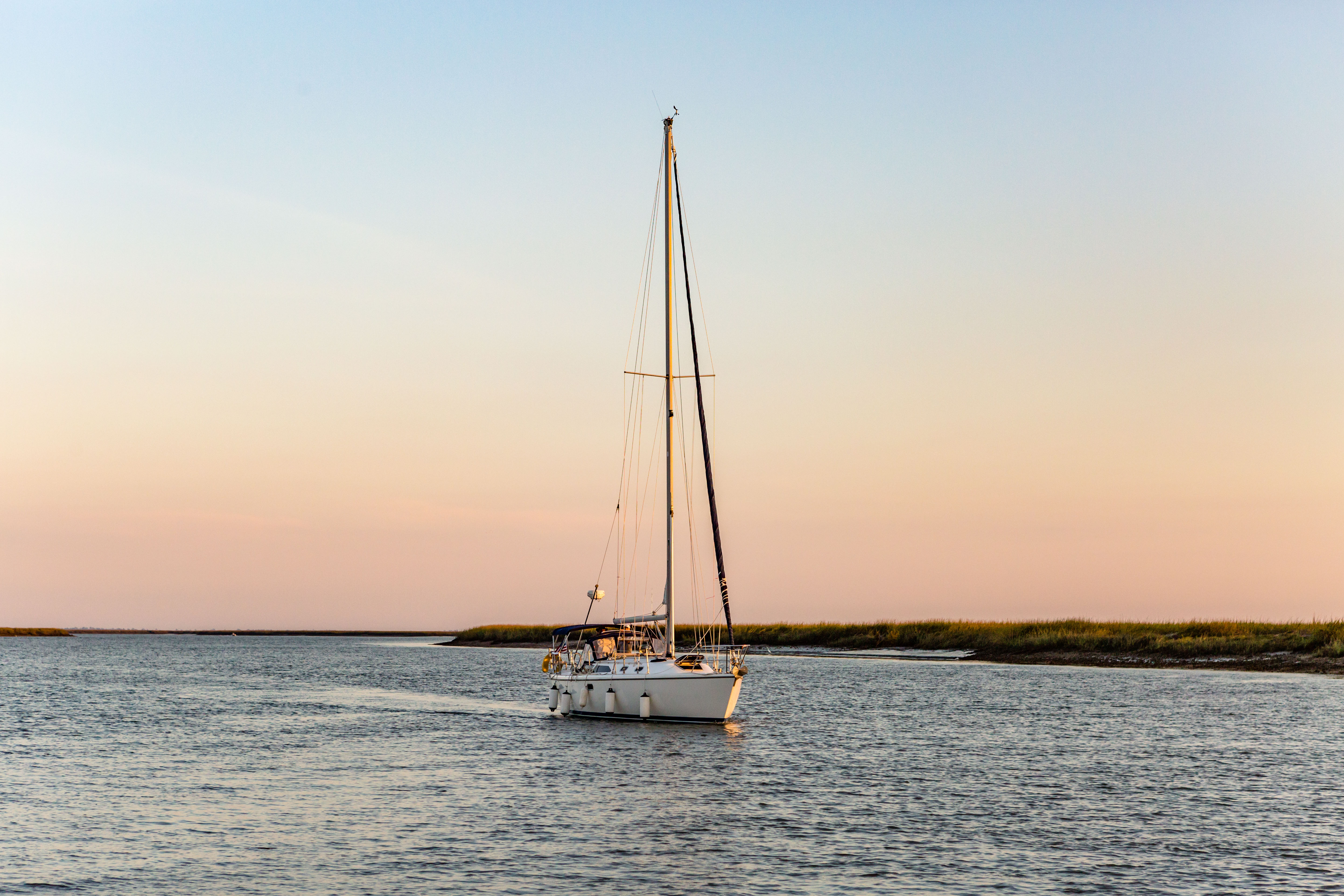 A sail boat on the ocean at sunset.