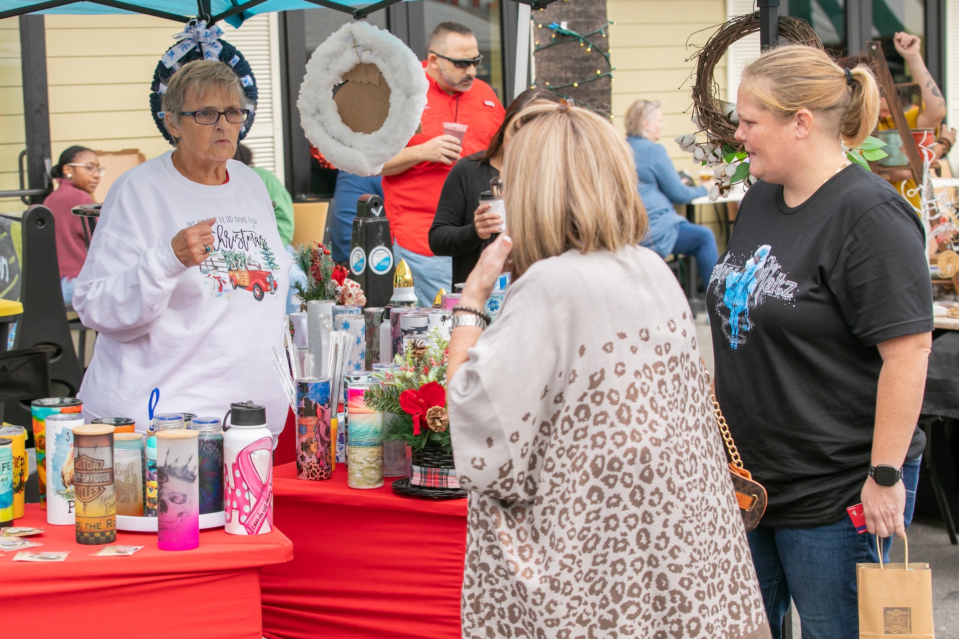 Tybee Holiday Market vendor and customers standing at a booth outdoors