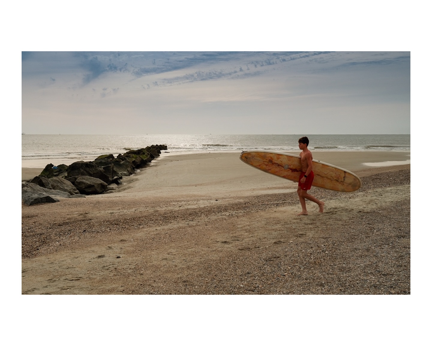 A young surfer heading towards the ocean on Tybee Island, GA.