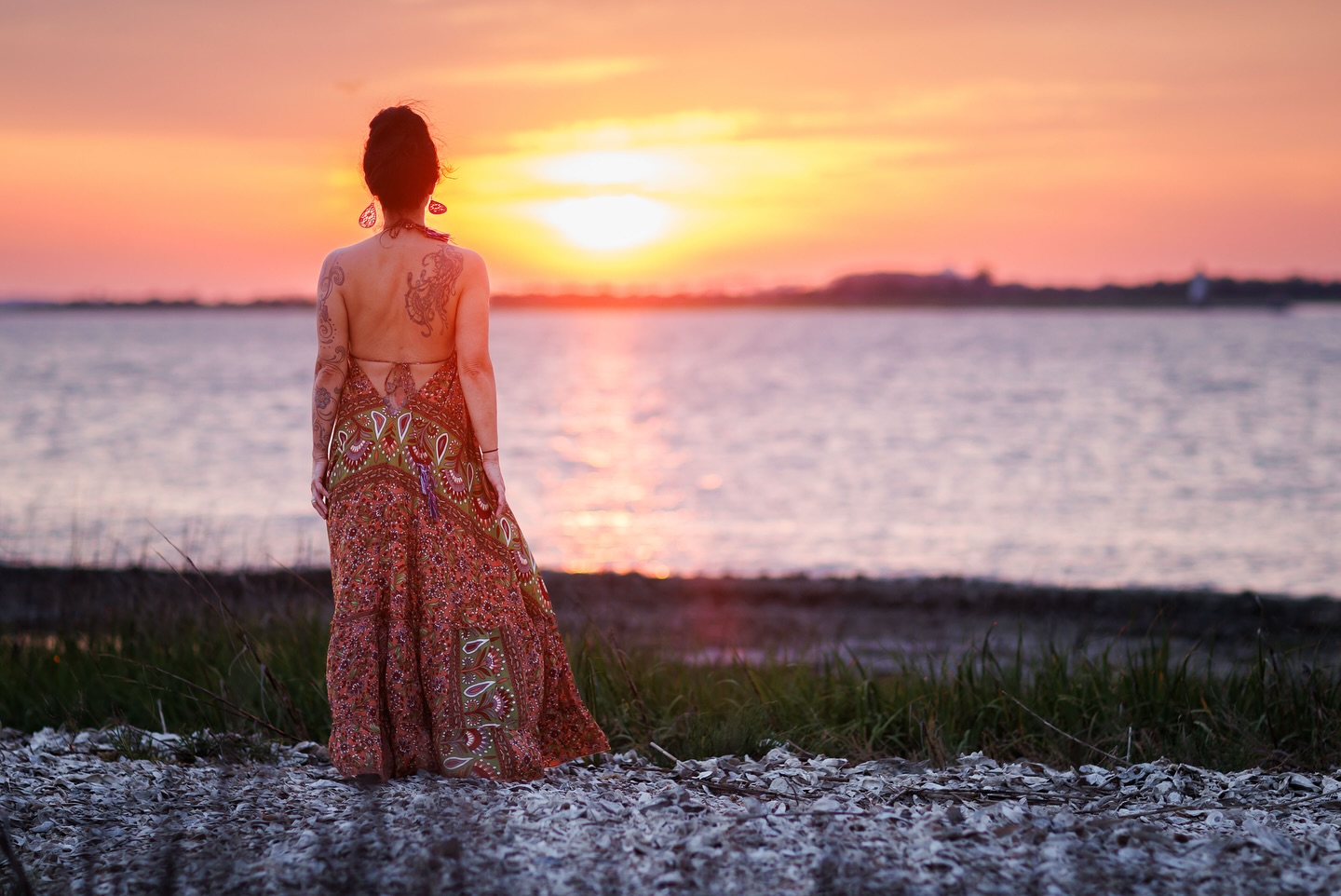A woman standing on the beach watching the sunset.