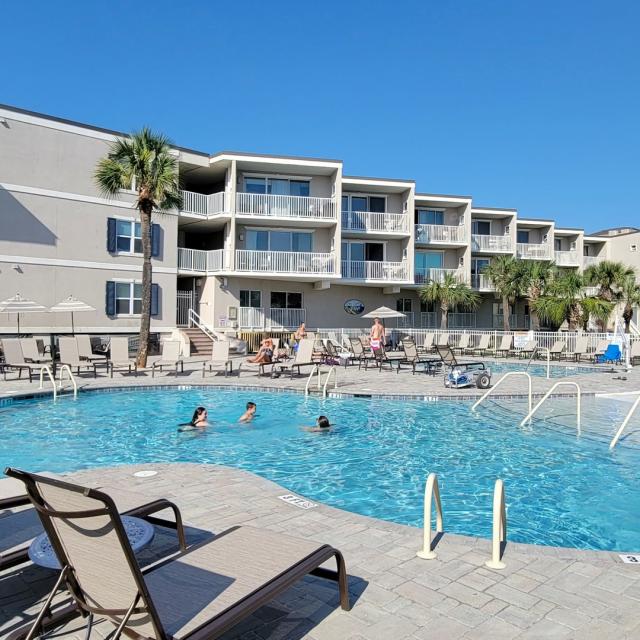 Resort condo and pool view with people swimming