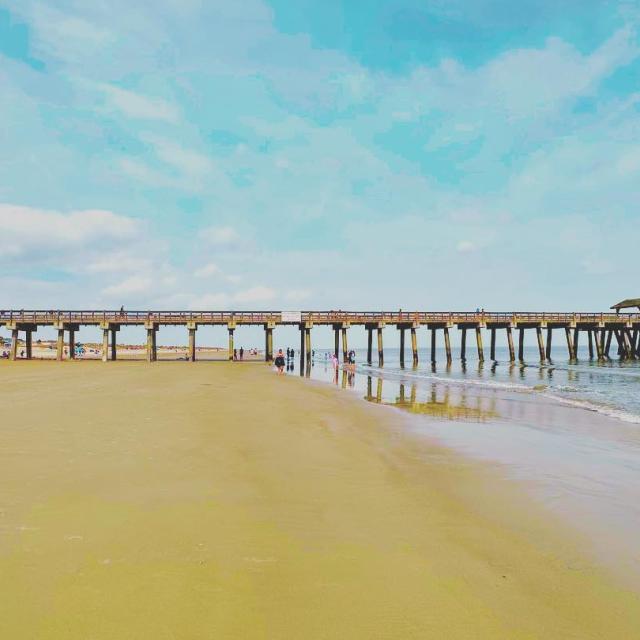 A sunny beach day with the view of a pier