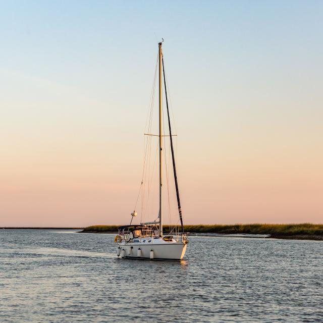A sail boat on the ocean at sunset.