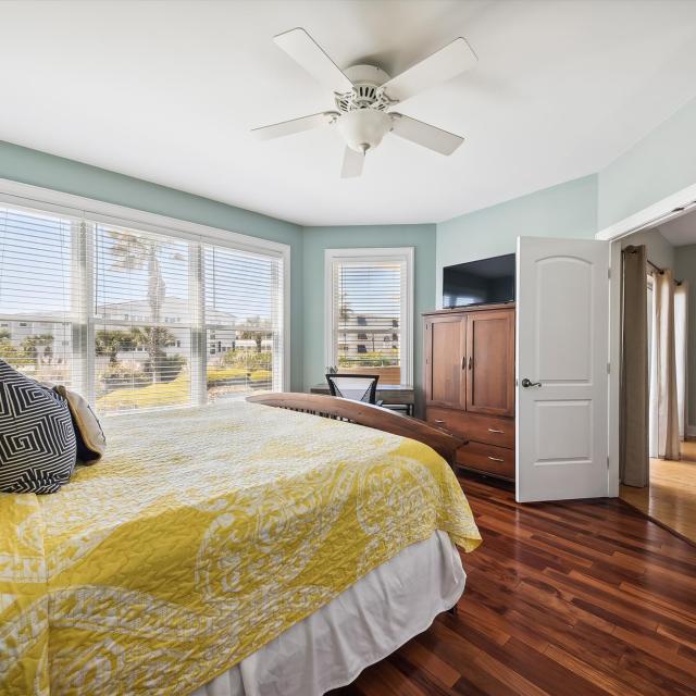 A large bedroom with a bed with a wardrobe, tv and desk.