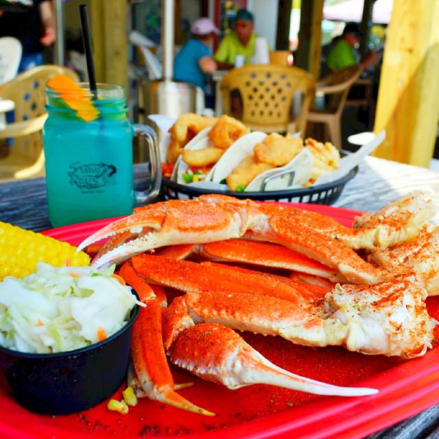 A seafood plate with crab legs, cole slaw and corn on the cob