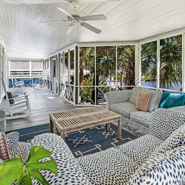 A large screened-in porch with couches and rocking chairs.