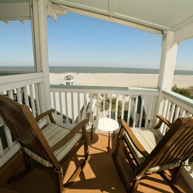 A balcony with rocking chairs with a view of the beach.