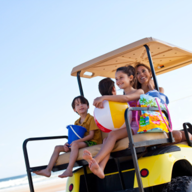 A family driving a golf cart on the beach