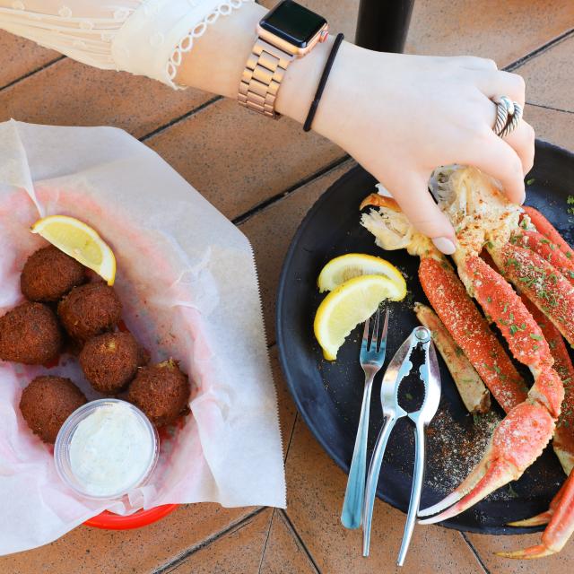 A hand reaching for crab legs arranged on a plate