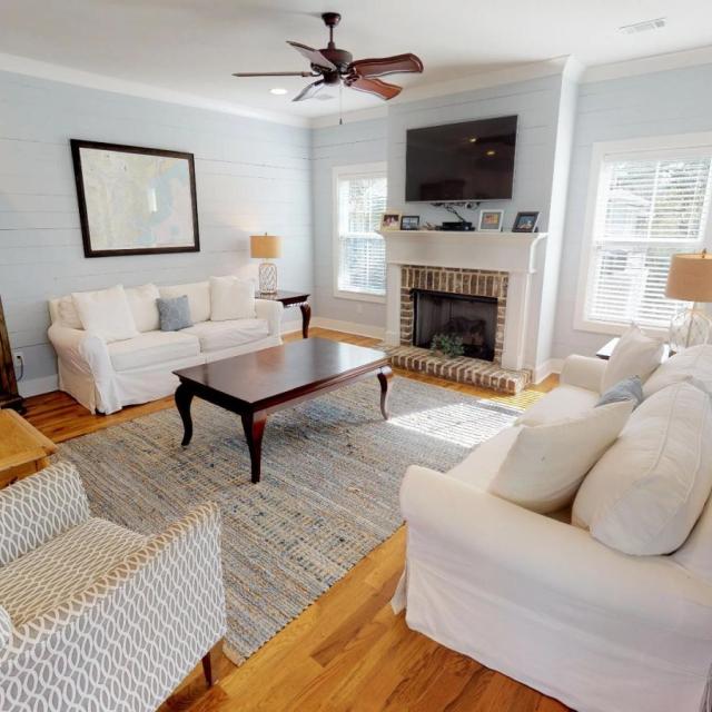 A living room with white seating and a fireplace