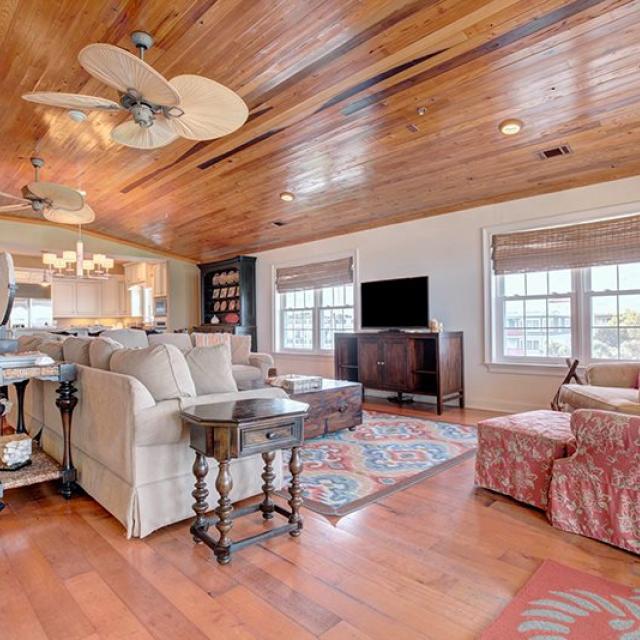 A spacious vacation home living room with seating and a view of the kitchen.