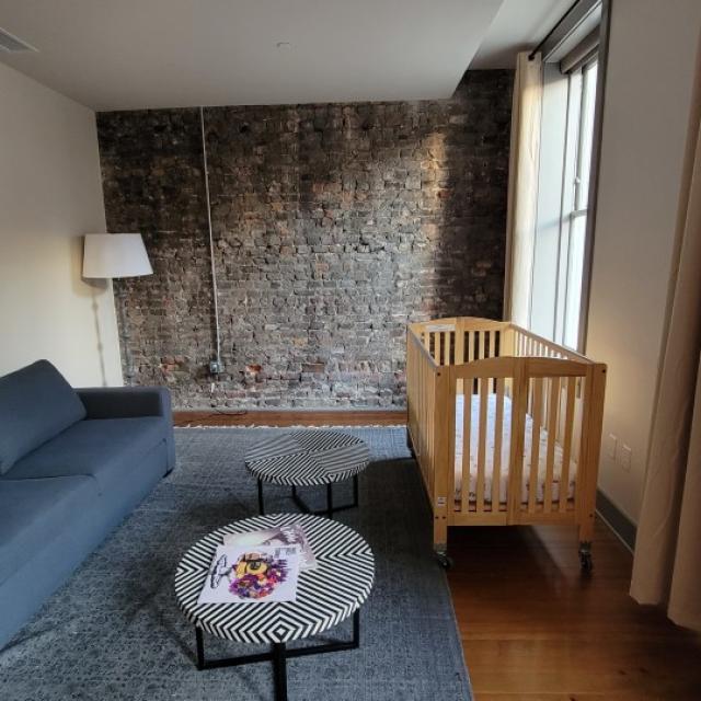 Living room with couch, small round tables and baby crib