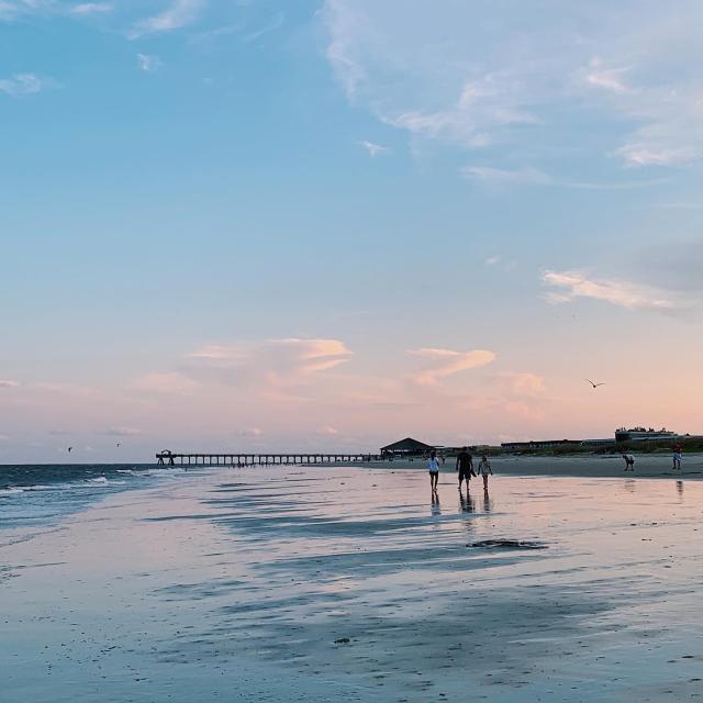 People walking on Tybee Island Beach with the pier in the background