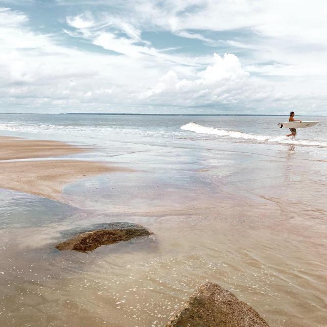 Surfer entering ocean on the beach