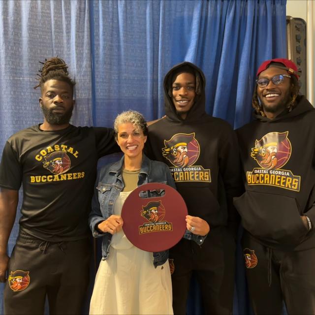 Three Coastal Buccaneers players and a woman