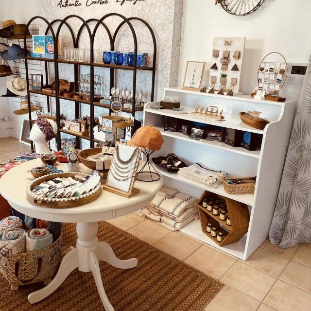 A retail store with shelves and a table of accessories such as jewelry, hats, headbands and scarves.