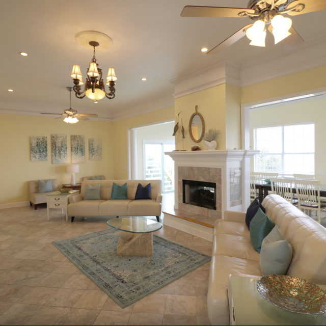 Evelyn’s Oasis 2nd floor main living area - white couches, ceiling fans, tile floors, yellow walls, fireplace and tv.