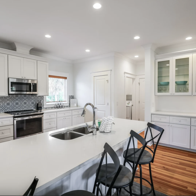 Large white kitchen with stainless steel appliances and wood floors