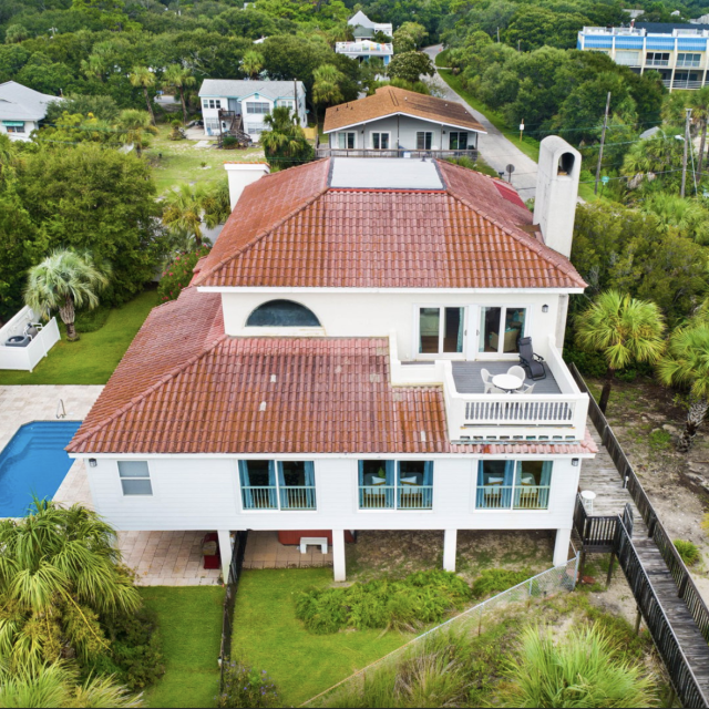 Outside view of the white two-story home, pool and balcony