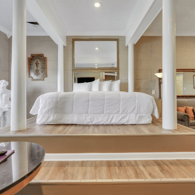 A Greek Mythology themed hotel suite with a large bed and white bedding.