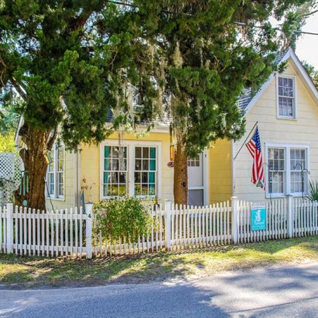 The outdoor front view of a yellow cottage home.