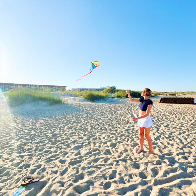 A woman on the beach flying a kite.