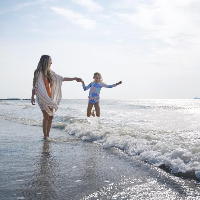 Mom and daughter on the beach playing in the ocean.