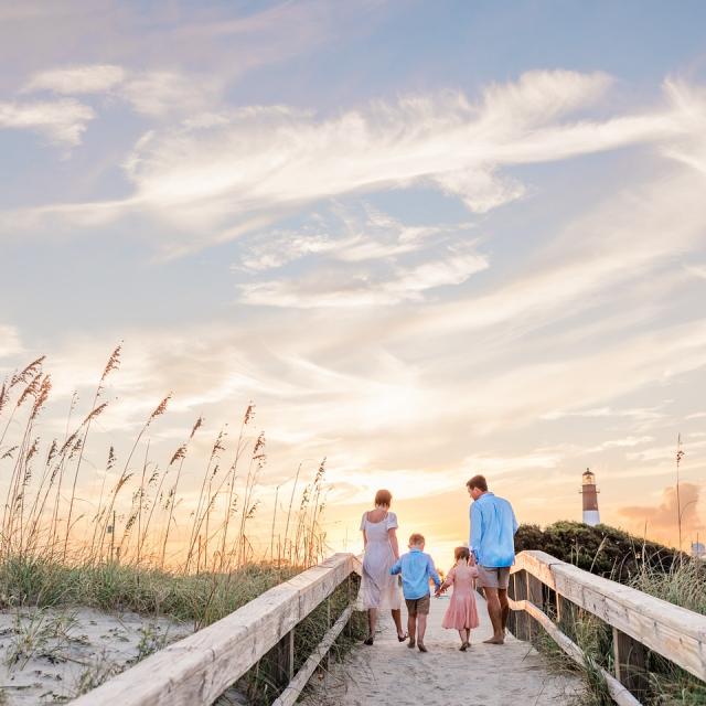 A family of four walking the dock towards the beach.