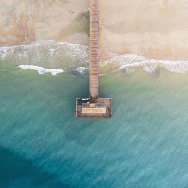 An aerial view of the top of a dock on the beach.