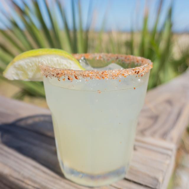 A cocktail drink sitting on a boardwalk at the beach.