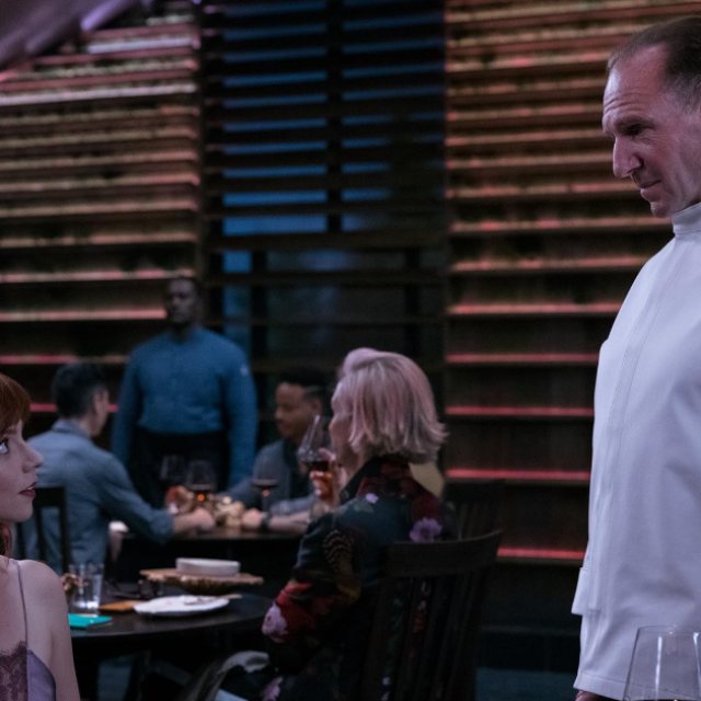 A woman speaking to a chef in a restaurant.