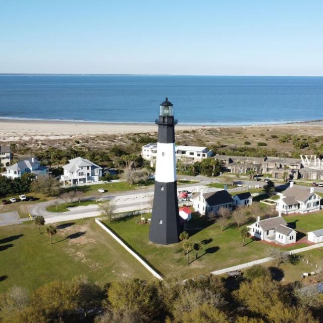 An aerial view of a lighthouse in the center of a small beach town.