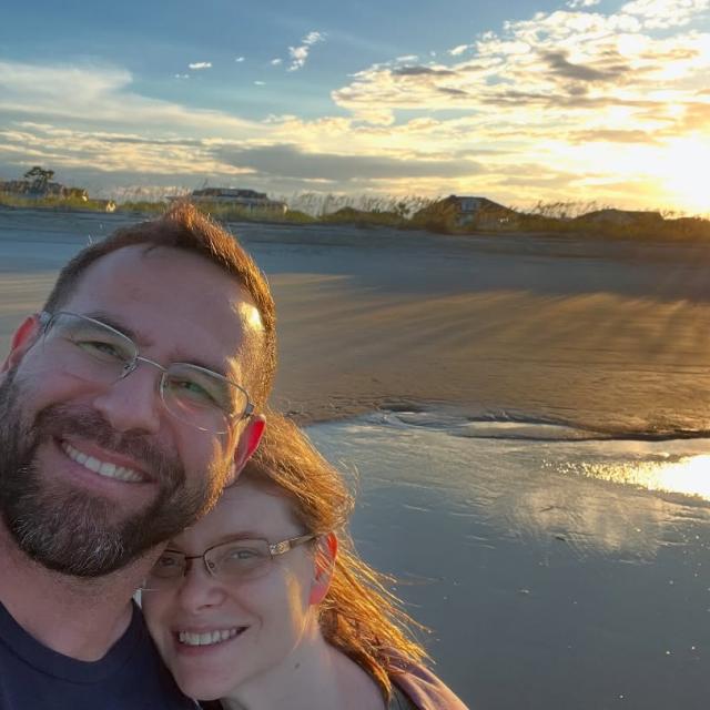 A couple taking a selfie on the beach at sunset.
