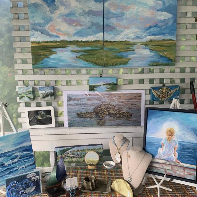 A variety of paintings and handmade jewelry available for purchase in an art gallery.