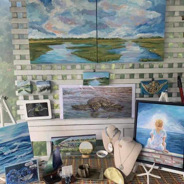 A variety of paintings and handmade jewelry available for purchase in an art gallery.