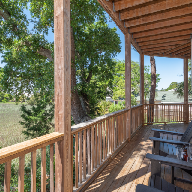 Sunset Hammock rental balcony overlooking Tybee Island’s serene marshes with Adirondack chairs.