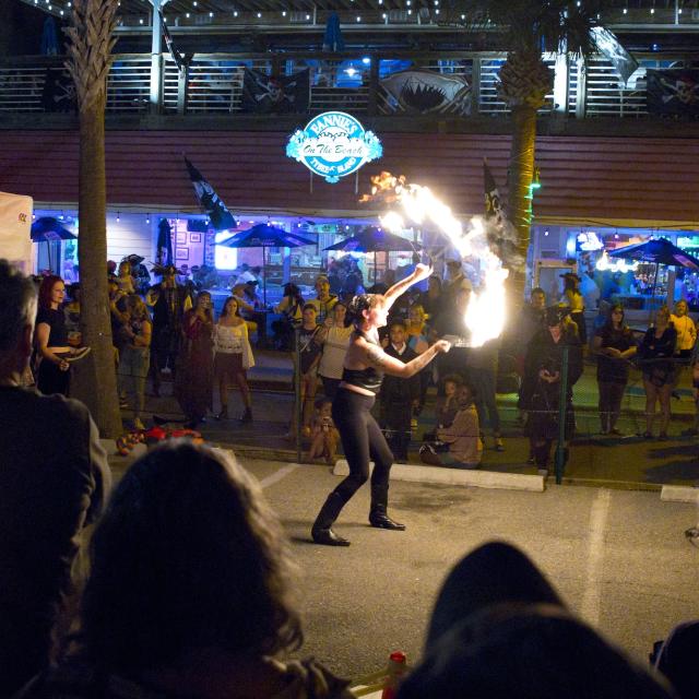 A woman performing fire acts outdoors as night at a carnival