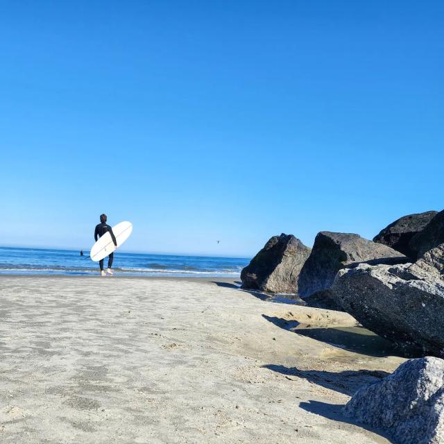 A surfer walking out to the ocean on Tybee Island, GA.