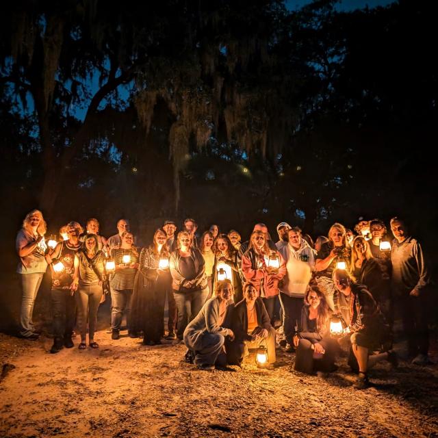 A large group holding lanters in a cemetery after dark.