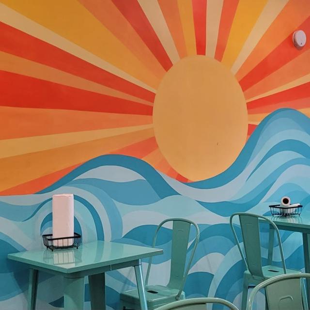 A restaurant wall mural of sunshine and ocean waves.