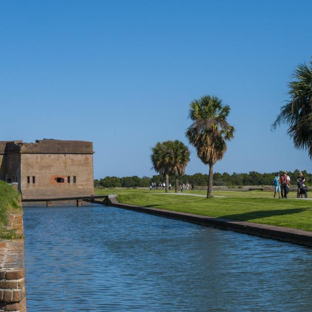 Tree-lined nature trail near Fort Pulaski with visitors walking.