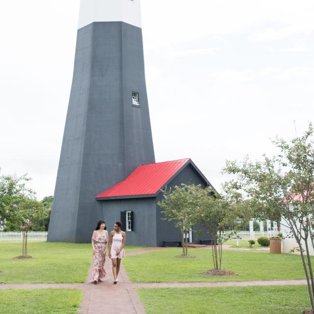 Two women walking the grounds of a lighthouse.