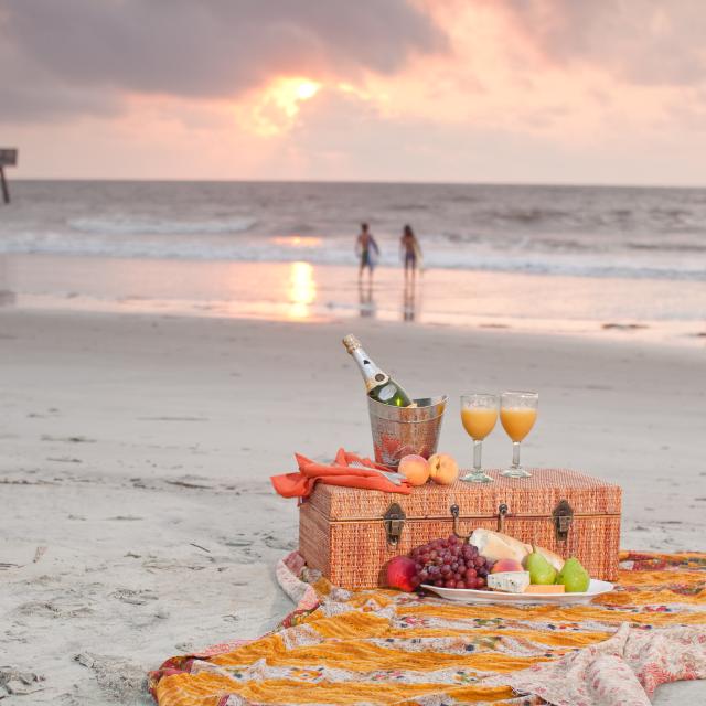 A picnic basket sitting on a blanket on the beach