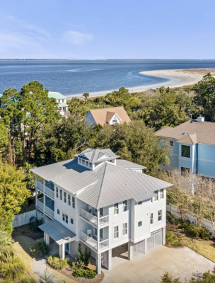 Aerial view of Oceanfront Cottage Rentals’ Tybee Oasis rental home with a view of the ocean, beach and blue sky