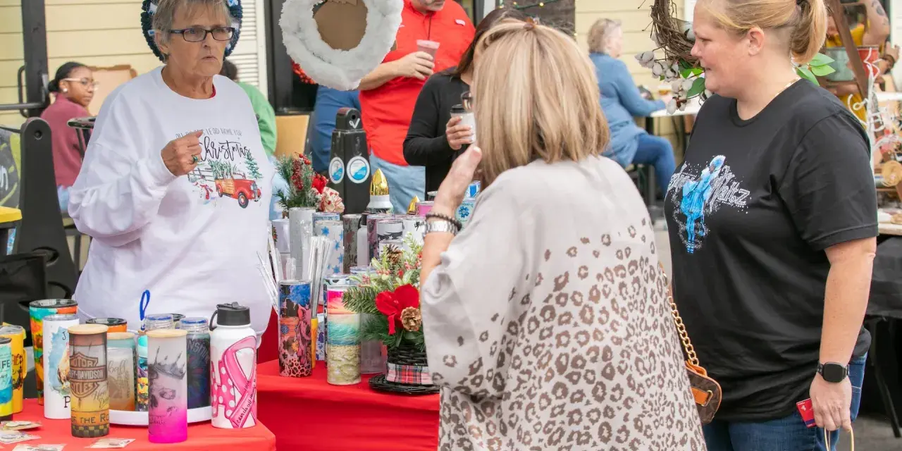 Tybee Holiday Market vendor and customers standing at a booth outdoors