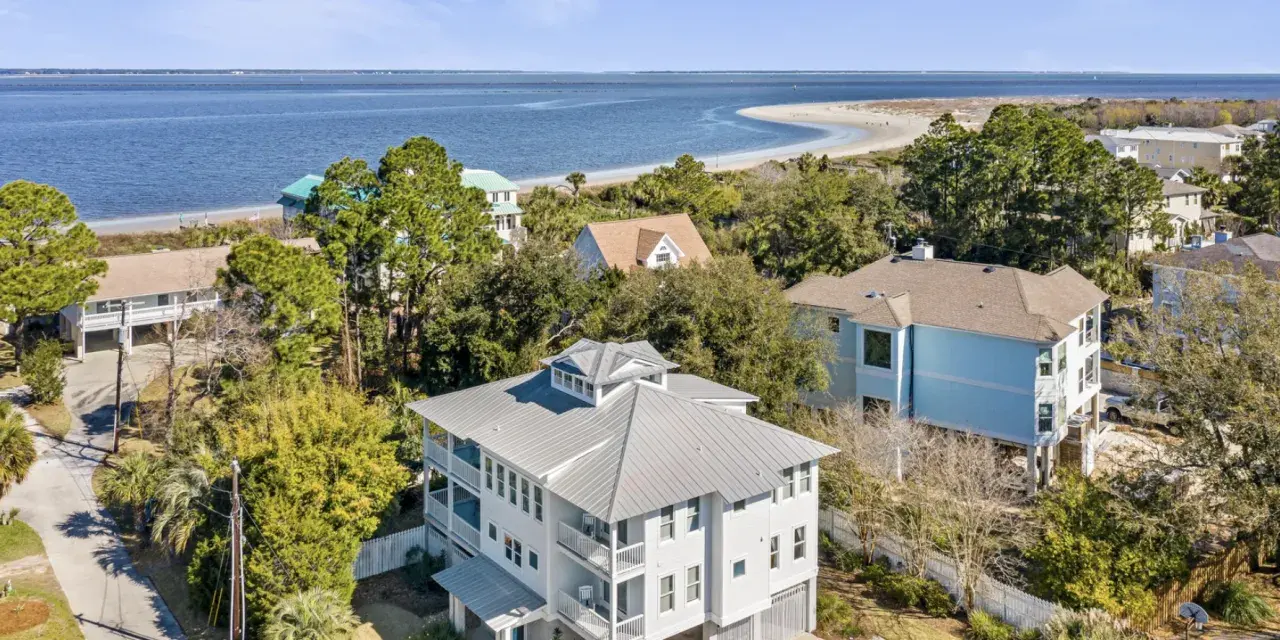 Aerial view of Oceanfront Cottage Rentals’ Tybee Oasis rental home with a view of the ocean, beach and blue sky