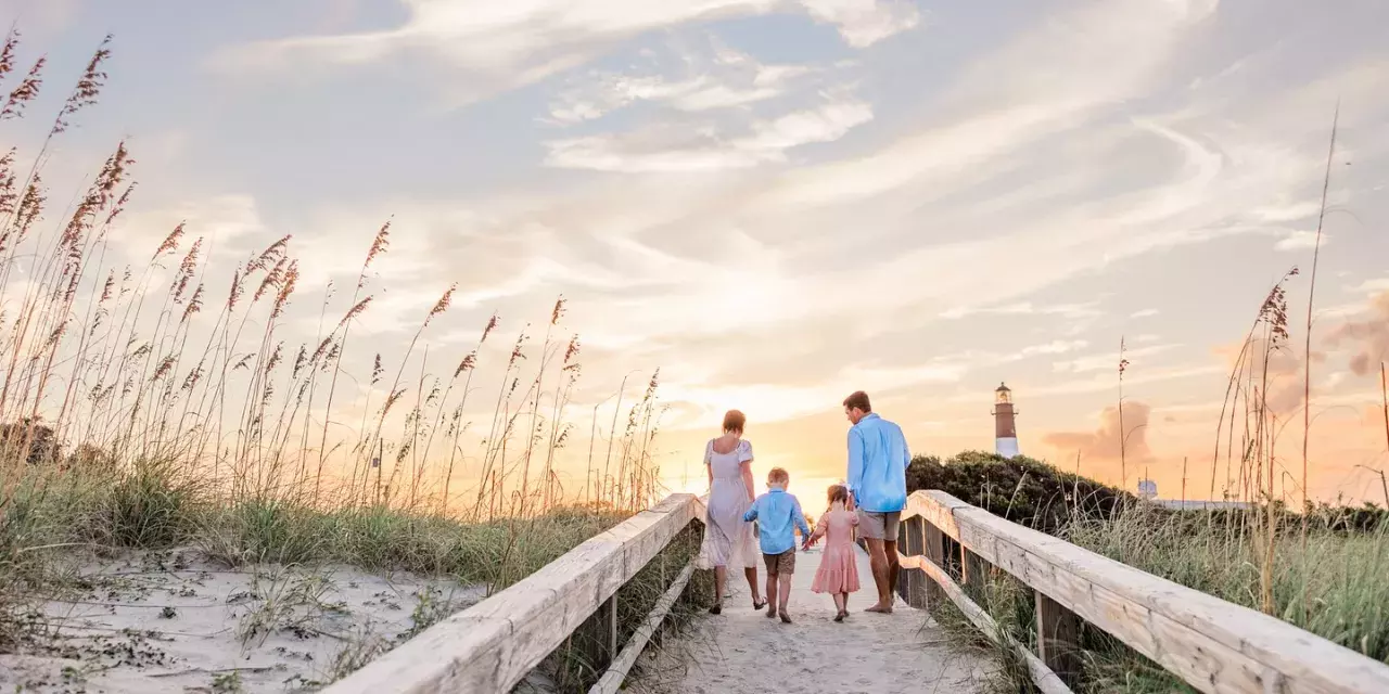 A family of four walking the dock towards the beach.