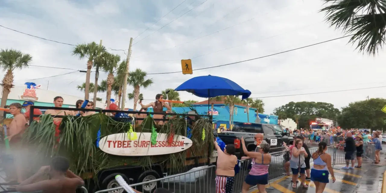 A parade with people on floats and spectators using water guns.