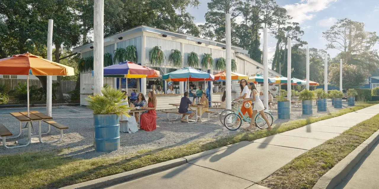 People eating outdoors at a restaurant with colorful rainbow umbrellas.