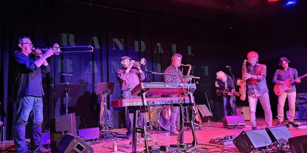 A four man band performing on stage.